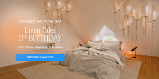 A styled bedroom scene with a bed dressed in light beige and white linens, surrounded by many floating translucent balloons. Large overlaid promotional text reads 'The Biggest Sale of the Year Linen Tales 13th Birthday 25% Off for Newsletter Subscribers' with a blue 'Subscribe & Save 25%' button. 