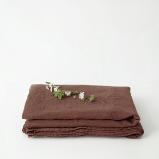 Folded chocolate brown linen flat sheet with a small branch on a white background 3